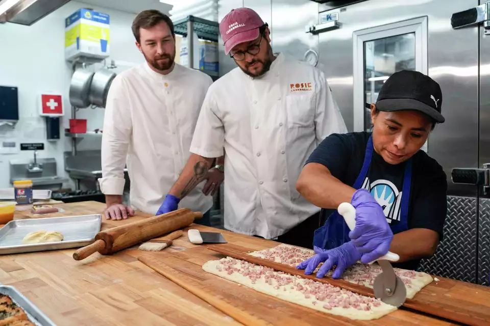 Delmy Miranda, right, cuts the dough as she finishes a Kolache di Recco, made in collaboration with chefs Austin Waiter, left, and Felipe Riccio, of Goodnight Hospitality, at the Kolache Shoppe in the Heights. By Brett Coomer/Houston Chronicle Staff photographer